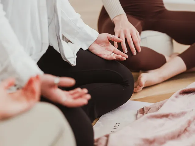 Participants sitting cross-legged with hands resting open on their knees during a breathwork session at Davaar House
