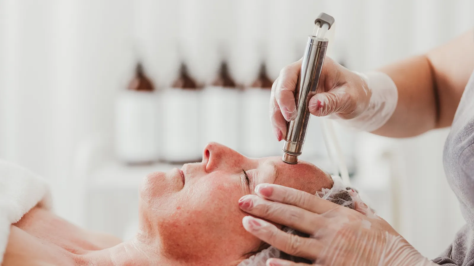 Therapist performing a facial treatment at Davaar House